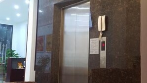 An elevator in a modern lobby with a marble wall and a phone mounted on the wall. - Camellia Hotel (Ninh Binh)