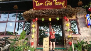 A restaurant named "Tam Gia Trang" with a traditional thatched roof entrance, colorful lanterns, and a signboard with Vietnamese text. - Camellia Hotel (Ninh Binh)