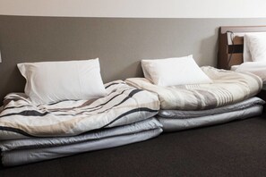A bed with a striped blanket and pillows, a headboard, and a wall-mounted shelf. - GH One More Heart Kyoto Station South 3 (Kyoto)