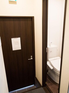 A narrow hallway with a wooden door, a white sink, and a toilet. - GH One More Heart at Toji 1 (Kyoto)