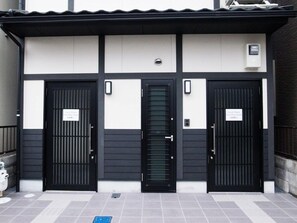 A building with three black doors, each with a sign above. - GH One More Heart at Toji 1 (Kyoto)