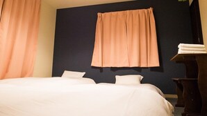 A bedroom with a bed, two pillows, a dark wall, a window with a curtain, and a plant. - GH One More Heart at Toji 1 (Kyoto)