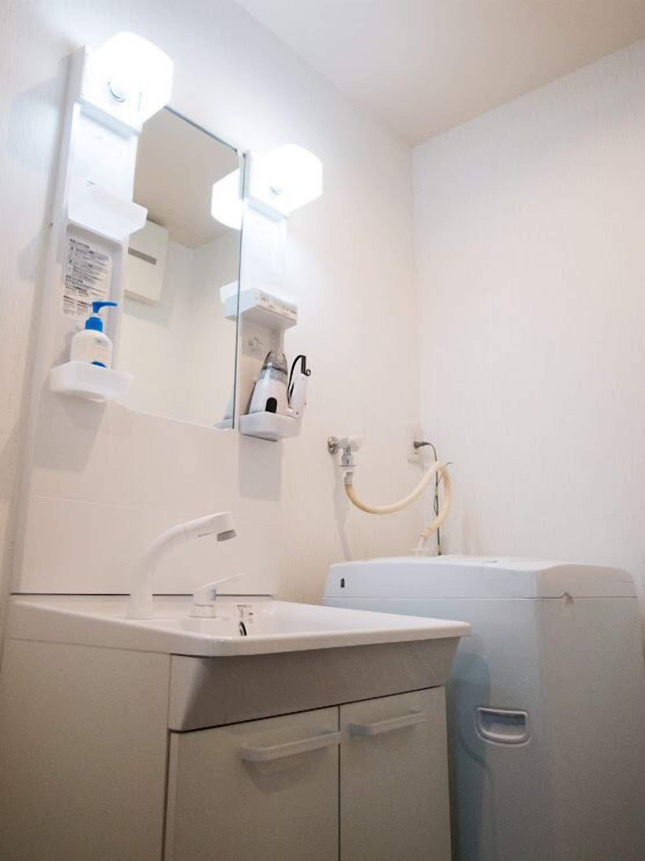 A bathroom with a white sink, mirror, and towel rack. There is a white cabinet with drawers and a towel rack.