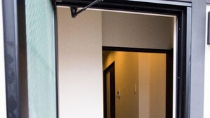 An open door leading to a hallway with a tiled floor and a light switch on the wall. - GH One More Heart at Toji 1 (Kyoto)