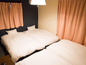 A hotel room with two beds, a nightstand, a lamp, and curtains. - GH One More Heart at Toji 1 (Kyoto)