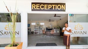 A reception area with a sign reading "RECEPTION," a reception desk, a television, and a bookshelf. - SAWAN Pool Villas Residence (Koh Samui)