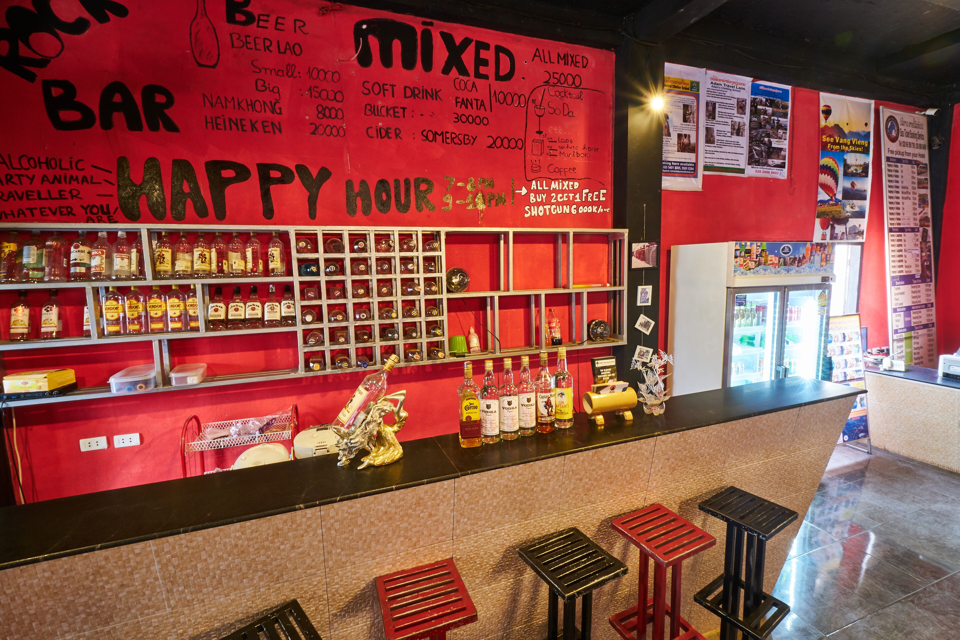 A bar area with shelves of bottles, a 'Happy Hour' sign, and stools.