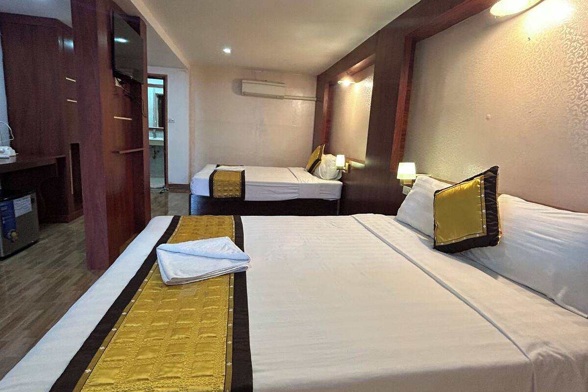 A hotel room with two beds, a desk, and a TV.