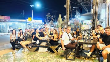Un grup de persones assegudes a taules a un pati exterior enrajolat.