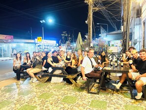 A group of people seated at outdoor tables on a tiled patio area. - Vang Vieng Rock Backpacker Hostel (Vang Vieng)