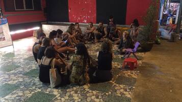 A group of people sitting on a tiled floor outdoors, possibly in a courtyard or public space.