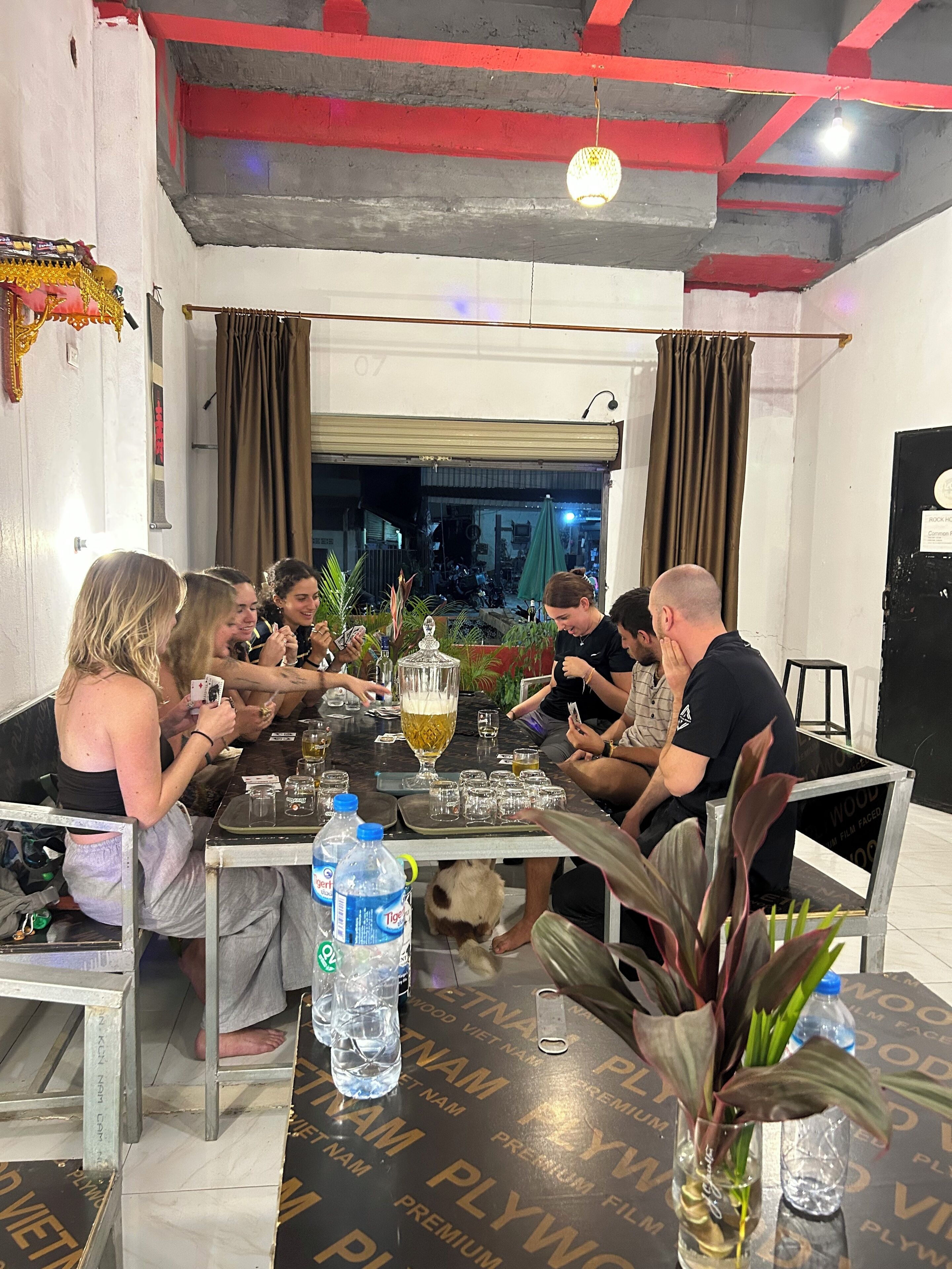 Eine Gruppe von Personen sitzt an einem Tisch, auf dem sich eine Wasserflasche, ein Glas und eine dekorative Vase befinden.
