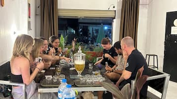 Eine Gruppe von Personen sitzt an einem Tisch, auf dem sich eine Wasserflasche, ein Glas und eine dekorative Vase befinden.