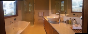 A modern bathroom with a glass-enclosed shower, a freestanding bathtub, a large vanity with a sink, and a mirror.