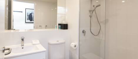 A modern bathroom with a glass-enclosed shower, a white sink, and a toilet.