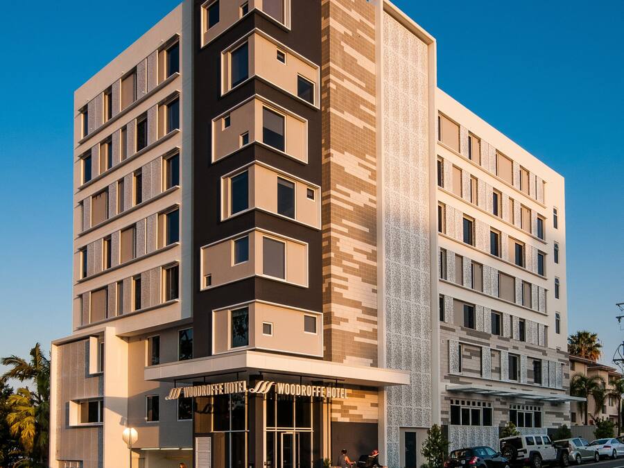 Un hotel moderno con una entrada destacada, varios pisos y una vista despejada de la calle.