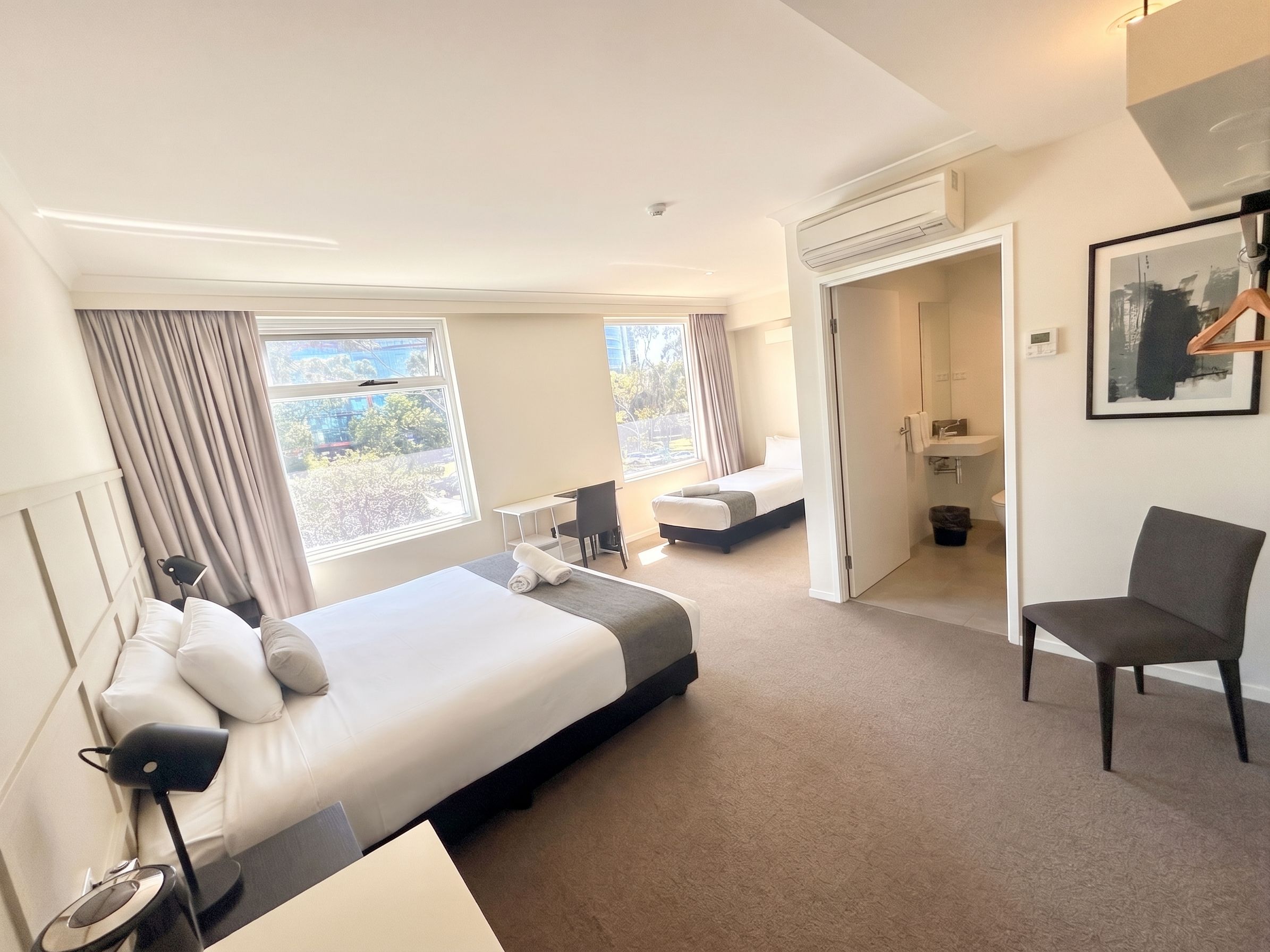 Una habitación de hotel con una cama grande, un escritorio, una silla y un baño.
