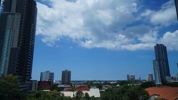 Une vue sur une ville avec de hauts immeubles, un ciel dégagé et une vue lointaine sur l’océan.