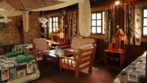 Een rustieke kamer met stenen muren, houten meubilair en een groot bed met een geborduurde sprei.