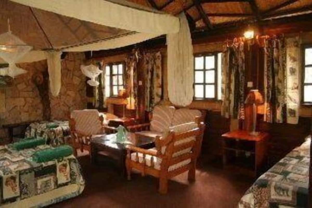 A rustic room with stone walls, wooden furniture, and a large bed with a patterned bedspread.
