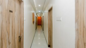 A hallway with wooden doors, numbered 101, leading to a room with a red accent wall. - OYO 3769 Blue Pearl Residency (Mumbai)