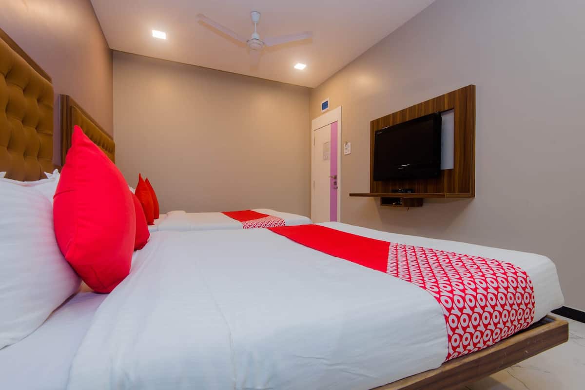 Ein Hotelzimmer mit Bett, Deckenventilator, an der Wand montiertem Fernseher und einer Tür mit einem pinken Streifen.