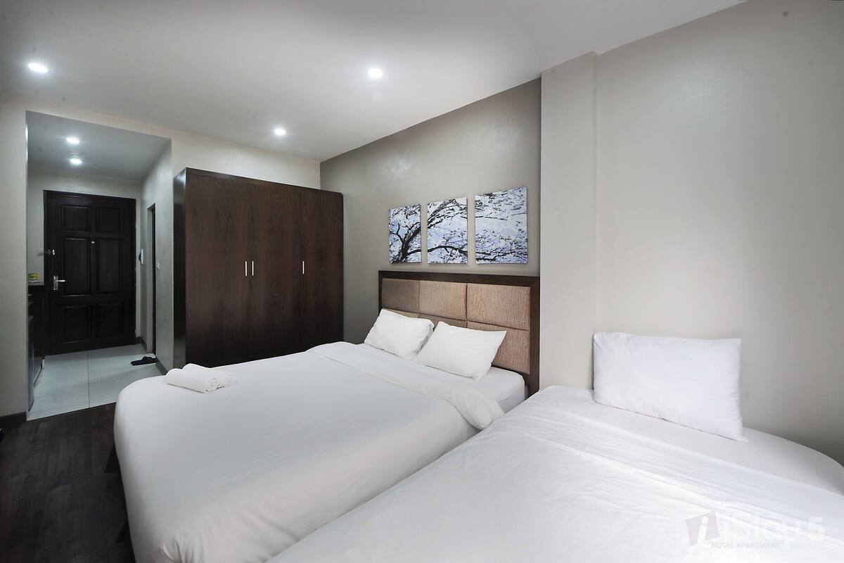 Un dormitorio de hotel con dos camas, un armario y un cuadro en la pared.