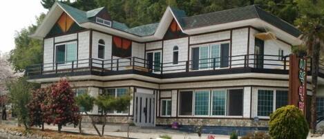 A two-story house with a balcony, large windows, and a stone foundation.