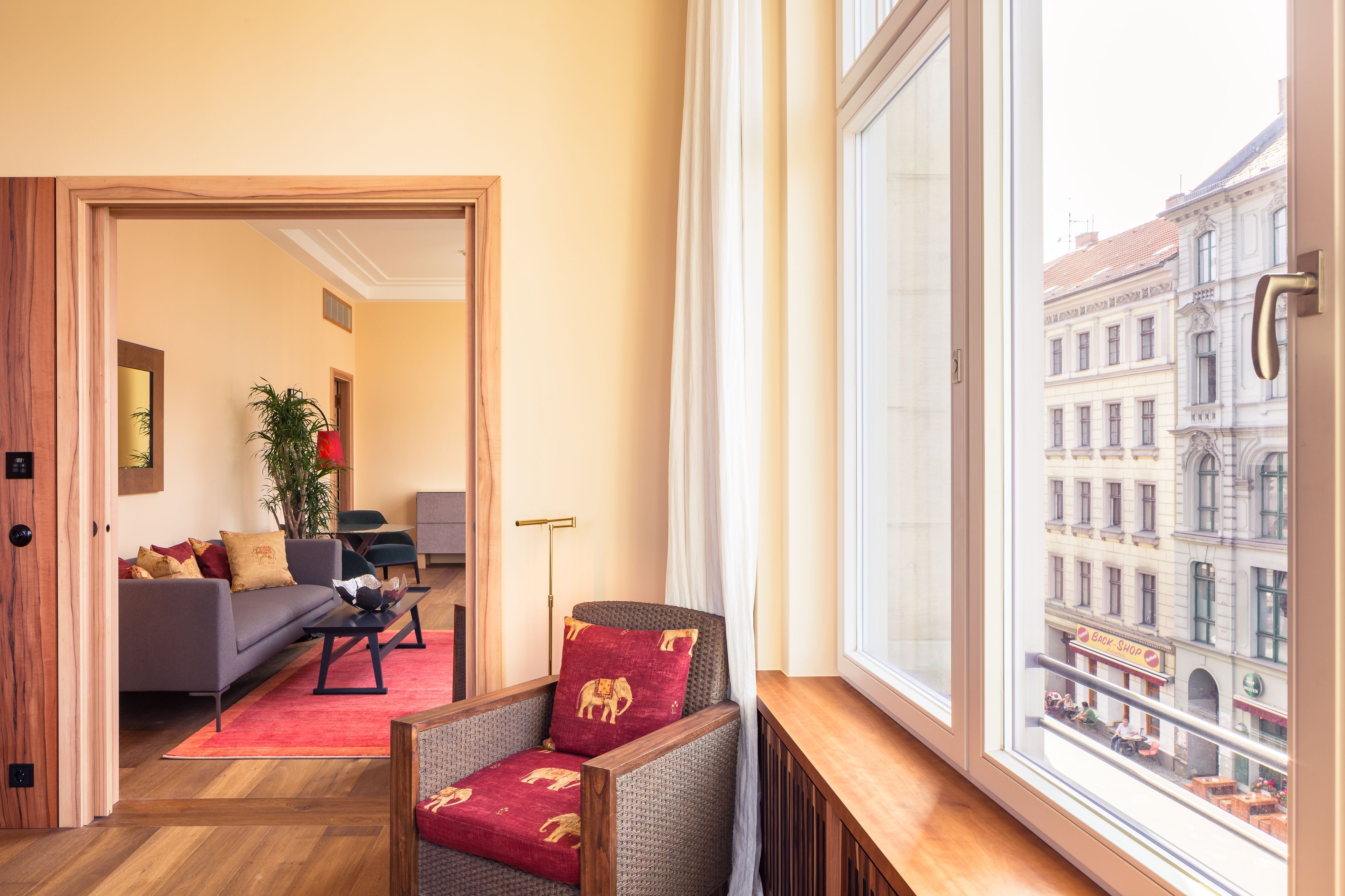 Una sala de estar moderna con un sofá, un sillón y vistas a la ciudad a través de un ventanal grande.