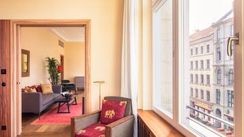 Una sala de estar moderna con un sofá, un sillón y vistas a la ciudad a través de un ventanal grande.