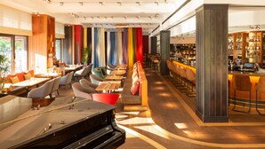 A modern restaurant with a bar area, seating arrangements, and a piano. - Orania.Berlin (Berlin)