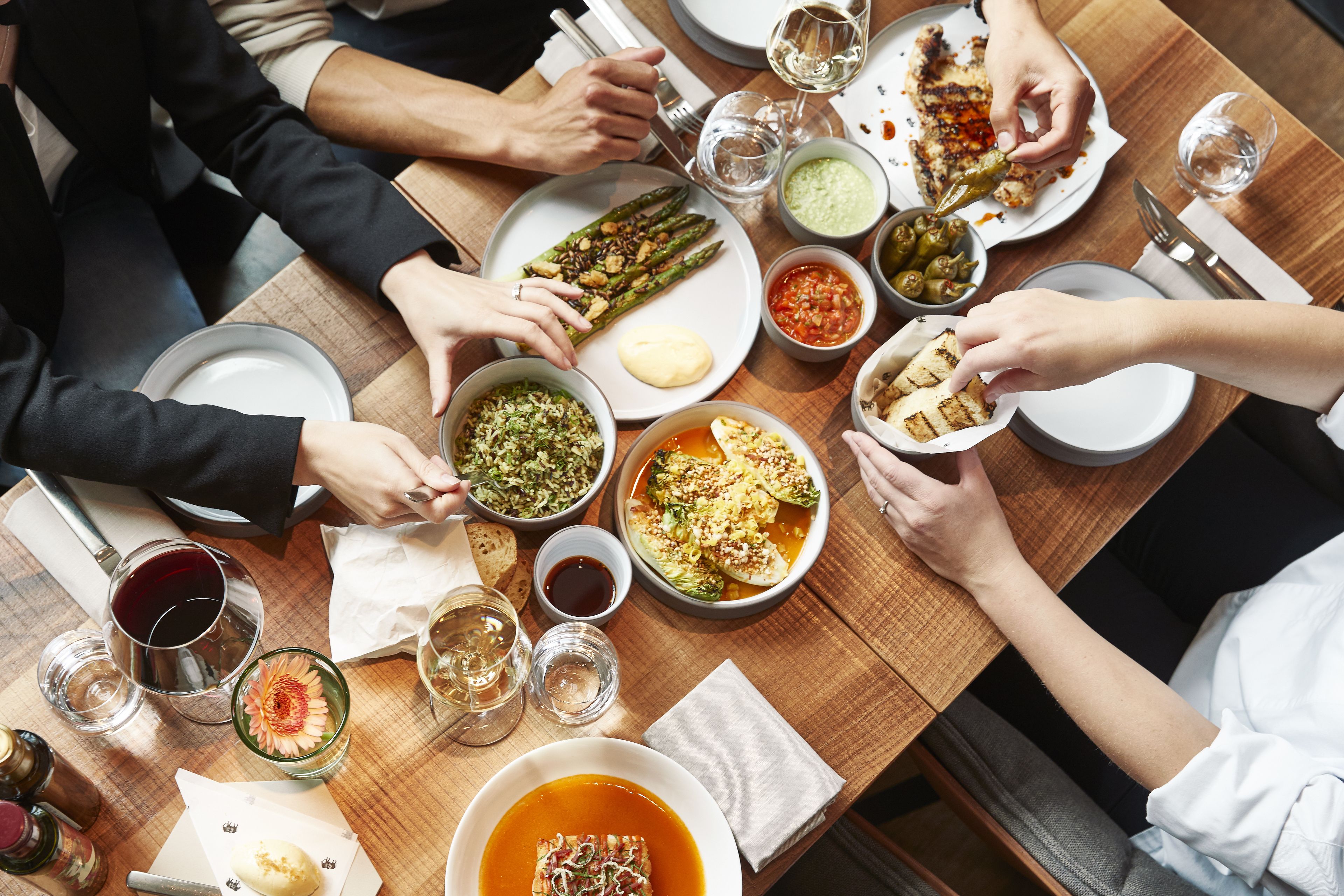 Una mesa de comedor con diferentes platos, copas de vino y cubiertos.