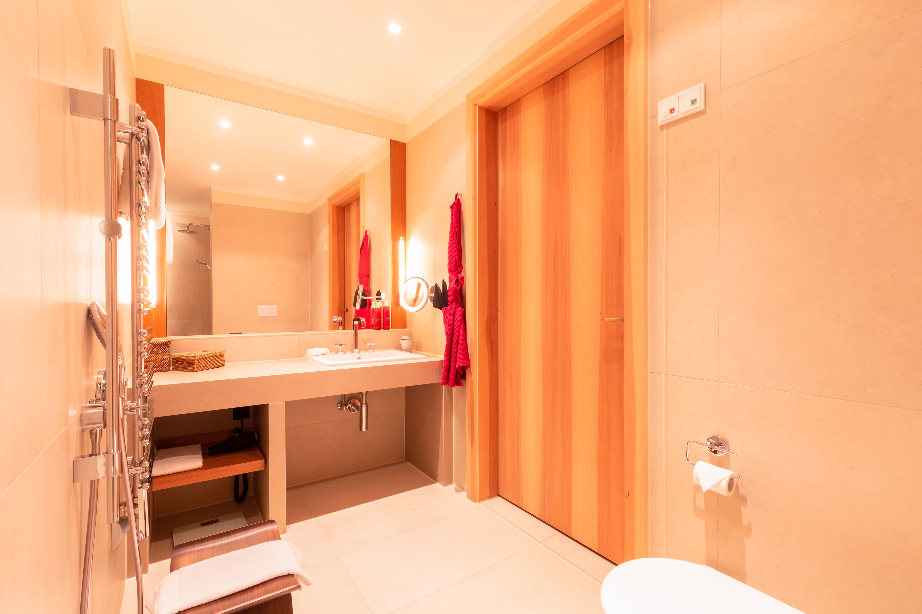 A modern bathroom with a large mirror, a sink, and a toilet.