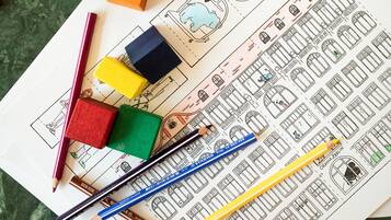 Une vue d’ensemble présentant des blocs de construction colorés, des crayons et une feuille de dessin avec des plans d’architecture.