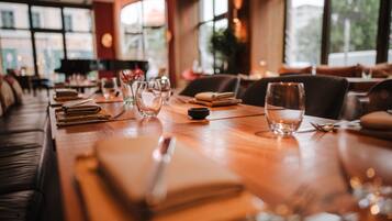 A restaurant with a wooden table set for dining, including plates, glasses, and cutlery.