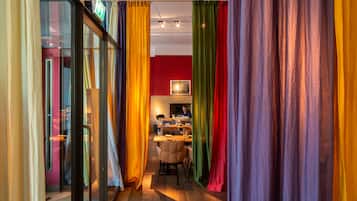 A modern interior with a glass partition, colorful curtains, a dining area, and a red accent wall.