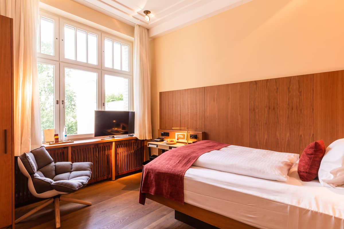 Ein Schlafzimmer mit Bett, Schreibtisch, Stuhl und Fernseher.