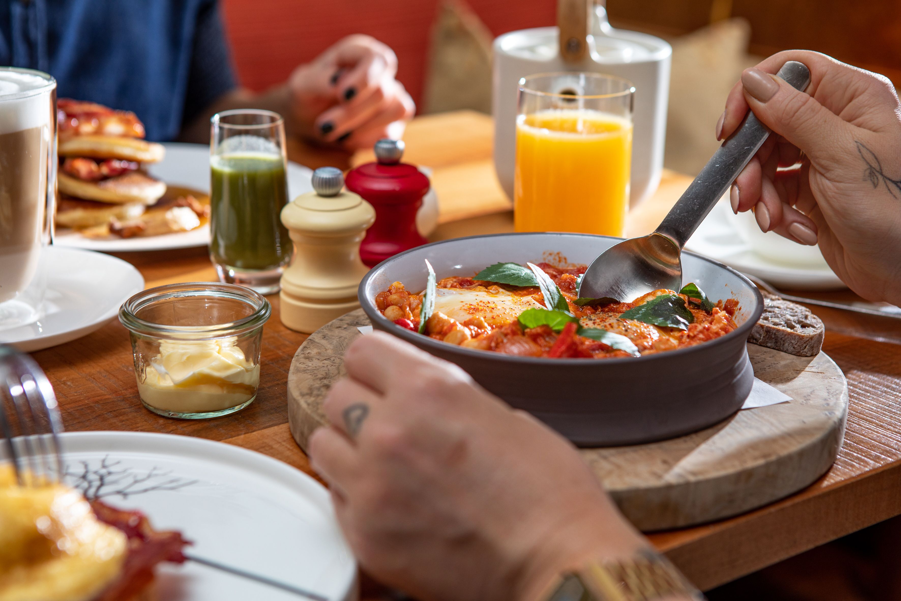Mesa de café da manhã com um prato de comida, um copo de suco de laranja e uma xícara de café.