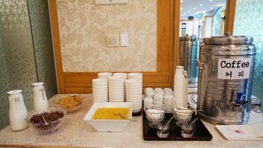Un buffet de petit-déjeuner avec divers plats, des distributeurs de café et une machine à café portant l’inscription « Café ».
