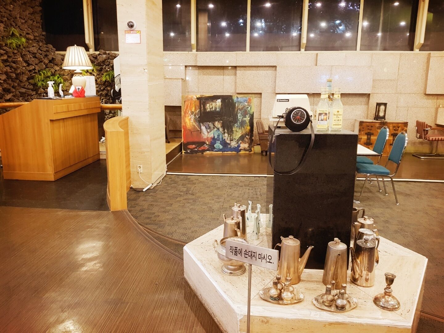 A lobby with a reception desk, a coffee station, and a painting on the wall.