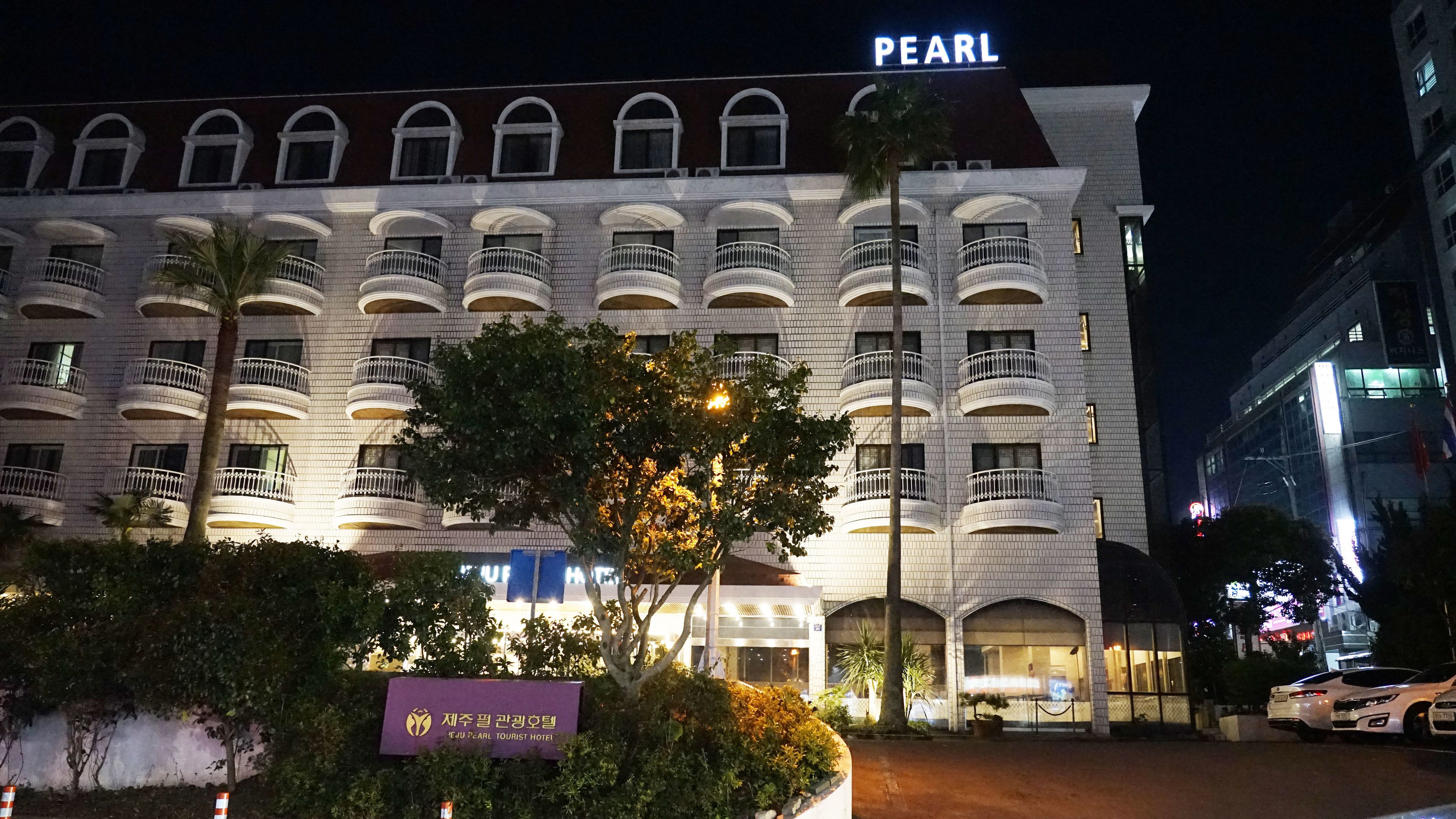 A multi-story hotel with a prominent "PEARL" sign, featuring balconies and a well-lit facade.