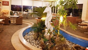 Een lobby met een fontein in het midden, zithoeken en een standbeeld.