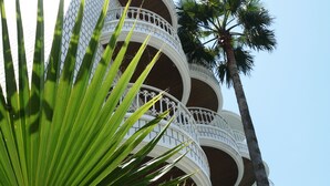 Een meerlaags gebouw met balkons en een palmboom.