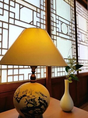 Une table avec une lampe jaune et un vase blanc contenant une plante.