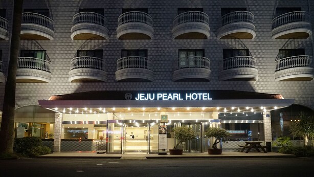 De gevel van het Jeju Pearl Hotel met meerdere balkons en een goed verlichte ingang.