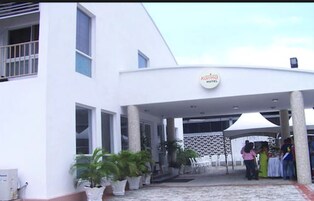 Entrada de un hotel con un área cubierta, plantas en macetas y un letrero que indica que es un hotel.