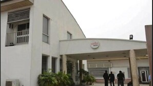 A building with a covered entrance, a sign above it, and a few people standing outside. - Karma Hotel (Lagos)