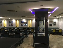 Un vestíbulo de hotel con varias zonas de estar, un mostrador de recepción y un pilar decorativo.