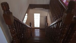 Una escalera de madera con barandilla que lleva a un rellano con ventana.