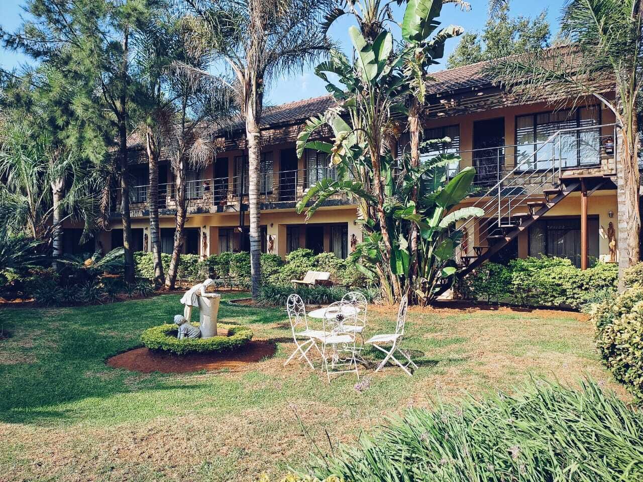A hotel with a central courtyard featuring a statue, outdoor seating, and lush greenery.